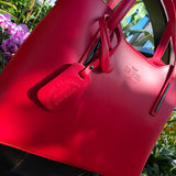 Red handbag with a visible brand logo against a natural background. - Don de Dieu Marque