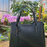 Black Italian handbag full view on a stone surface with blurred background. - Don de Dieu Marque