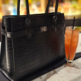 Black crocodile Italian leather handbag on a table with a blurred background. - Don de Dieu Marque