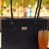 Black croc Italian leather handbag styled on a table with a cocktail in the foreground, blurred bar setting in the background. - Don de Dieu Marque