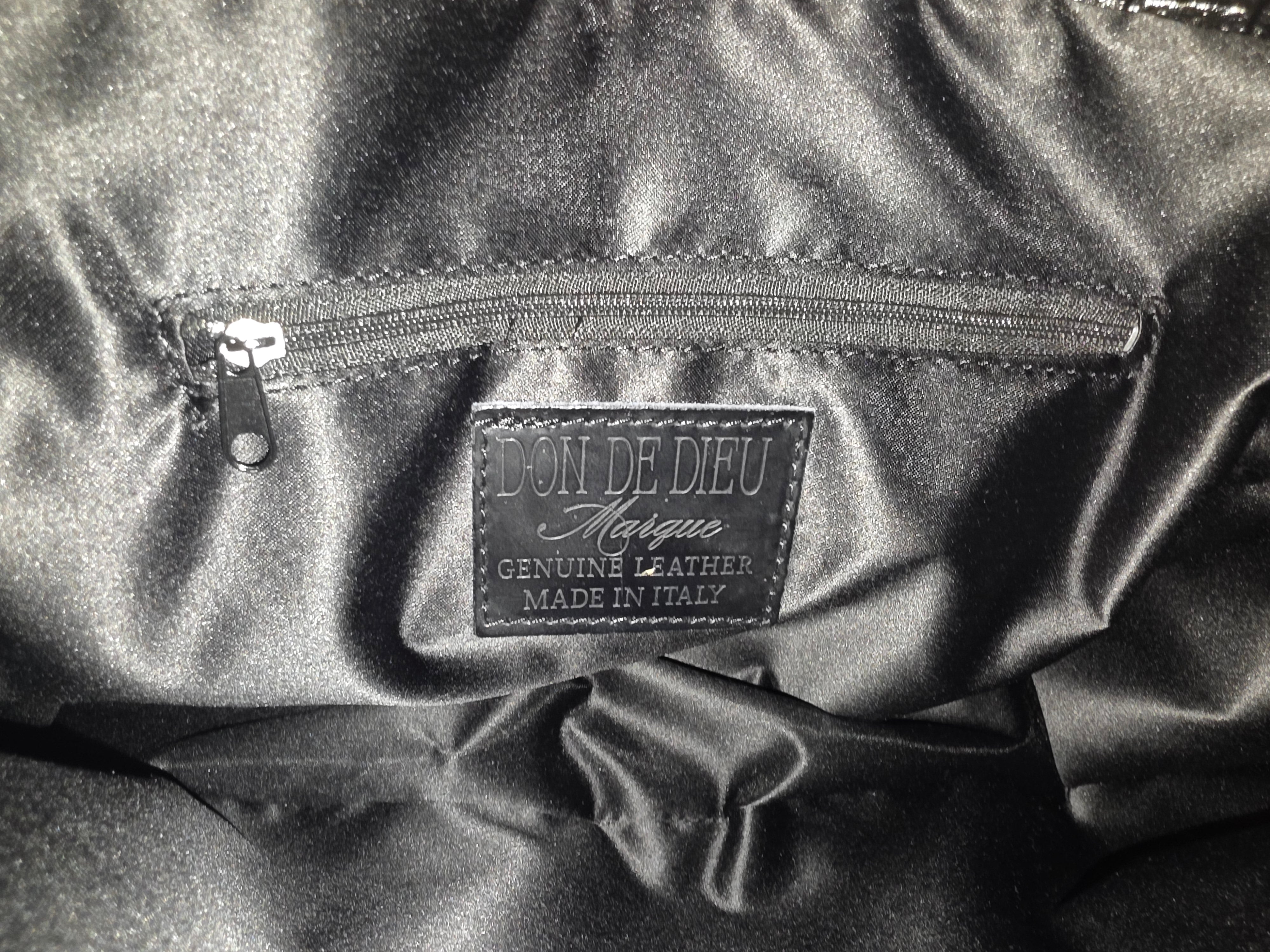 Close-up of a stitched label interior of leather handbag with 'Don de Dieu Marque Genuine Leather Made In Italy' branding.