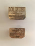 Two brass stamps engraved with our Brand logo on a light background what is used to hot stamp our logo collection bags. - Don de Dieu Marque 