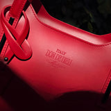 Up close detail of Red Italian leather handbag with 'Italy Don de Dieu' branding on a dark background - Don de Dieu Marque