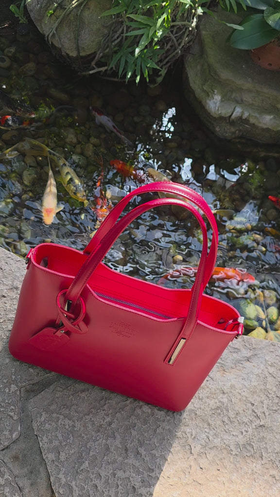 Red Italian leather handbag video view with Koi fish swimming in background pond garden. - Don de Dieu Marque